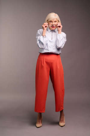 Elegant senior woman in white blouse and red pantsの写真素材
