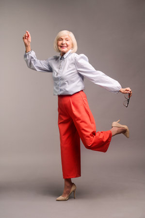 Happy senior woman in red pants and white shirtの写真素材