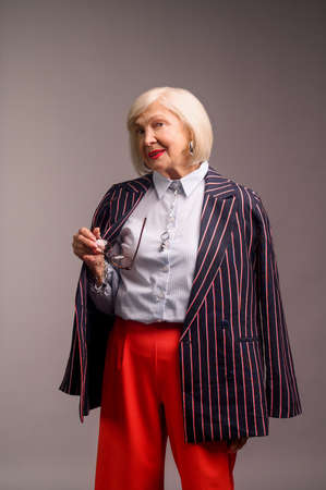 Blonde senior elegant woman in red pants and stylish jacketの写真素材