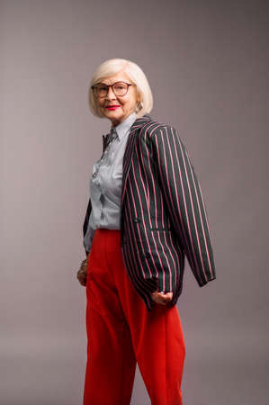 Blonde senior elegant woman in red pants and stylish jacketの写真素材