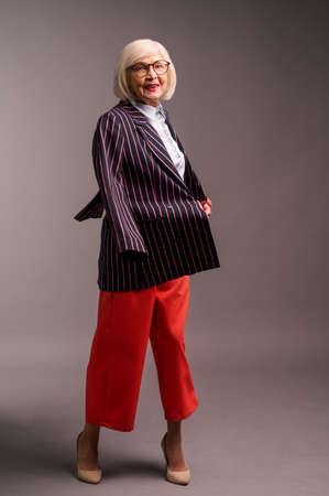 Blonde senior elegant woman in red pants and stylish jacketの写真素材