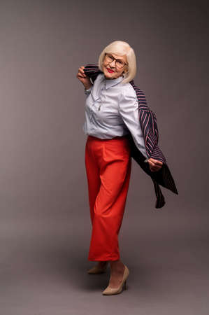Blonde senior elegant woman in red pants and stylish jacketの写真素材