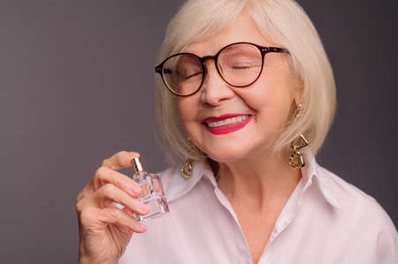 Waist up of senior woman with a perfume in handsの写真素材