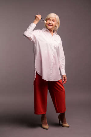 Stylish elegant senior woman holding a face brushの写真素材