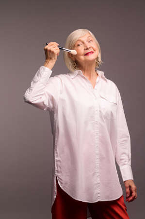 Stylish elegant senior woman holding a face brushの写真素材