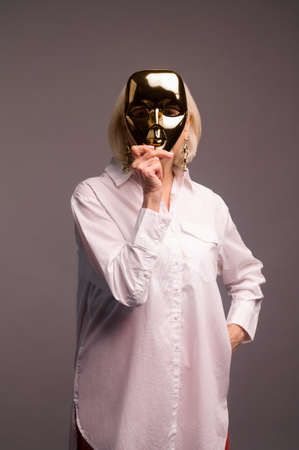 A woman in white shirt holding a masquerade maskの写真素材
