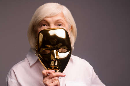 A woman in white shirt holding a masquerade maskの写真素材