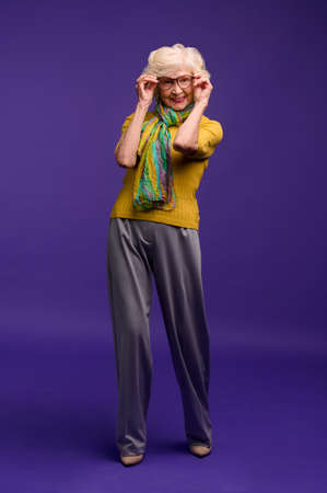 Senior woman in yellow shirt and with a green scarf looking carefreeの写真素材