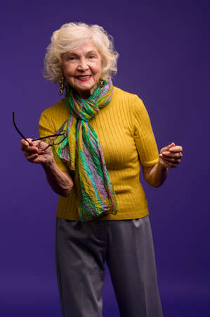 Senior woman in yellow shirt and with a green scarf looking carefreeの写真素材