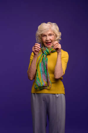 Senior woman in yellow shirt and with a green scarf looking carefreeの写真素材