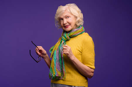 Senior woman in yellow shirt and with a green scarf looking carefreeの写真素材