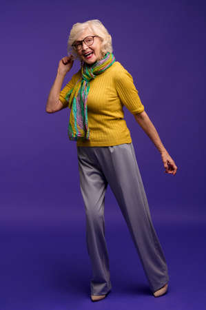 Senior woman in yellow shirt and with a green scarf feeling energizedの写真素材