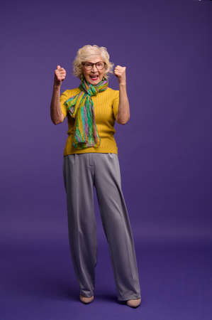 Senior woman in yellow shirt and with a green scarf feeling energizedの写真素材