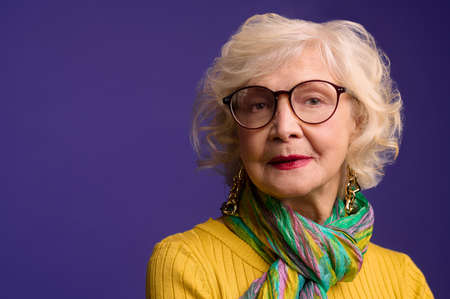 Pretty senior woman in eyeglasses looking confident and positiveの写真素材