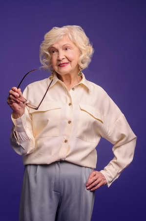 Elegant senior lady in eyeglasses in beige shirtの写真素材