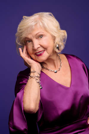 Senior blonde woman in an evening violet dress looking wonderfulの写真素材