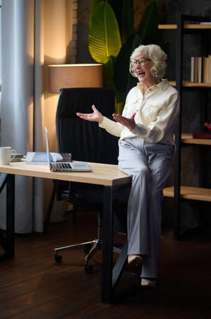 Woman sitting on table near laptop talkingの写真素材
