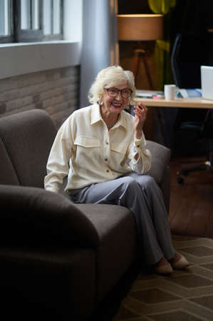 Woman in glasses smiling sitting on sofaの写真素材