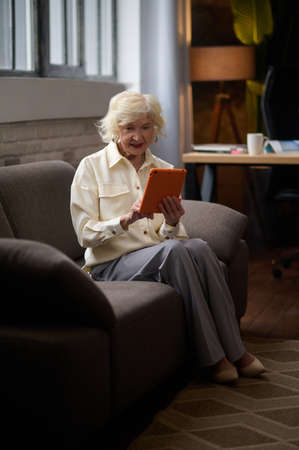 Woman sitting on couch looking at tablet.の写真素材