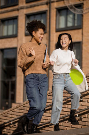 Two girls happily communicating climbing stairs outdoorsの写真素材