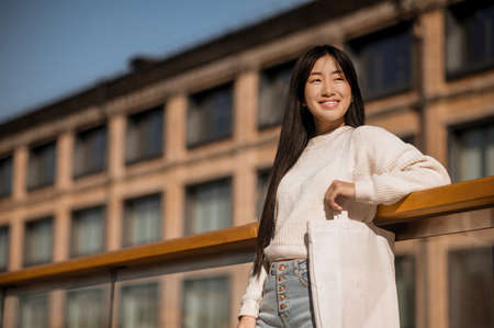 Girl with bag leaning on railing in streetの写真素材