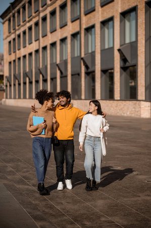 Two girls and guy talking walking down streetの写真素材