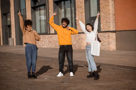 Excited guy and two girls with their hands upの写真素材