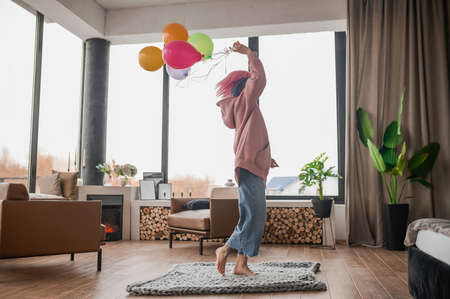 A happy girl dancing wiht a bunch of colorful balloonsの写真素材