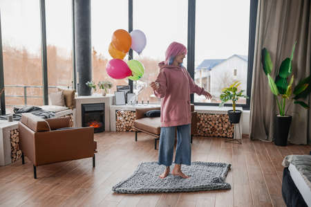 A happy girl dancing wiht a bunch of colorful balloonsの写真素材