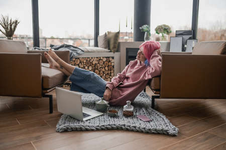A girl in a pink hoodie feeling relaxed at homeの写真素材