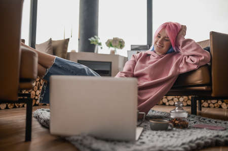 A girl in a pink hoodie feeling relaxed at homeの写真素材