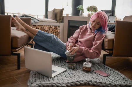 A girl in a pink hoodie spending a day at homeの写真素材