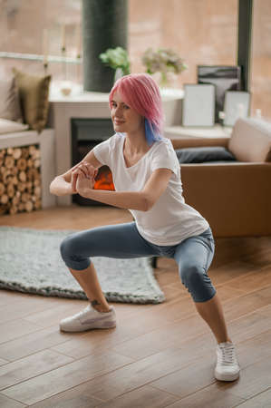 A girl in a white tshirt doing squatsの写真素材