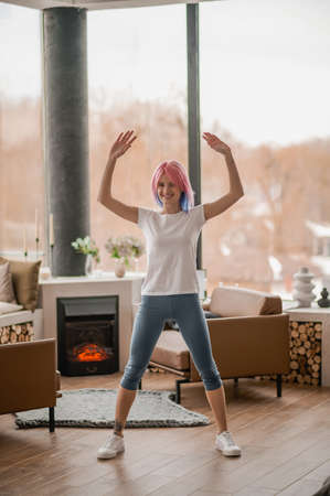 A girl with pink hair doing some exercising at homeの写真素材