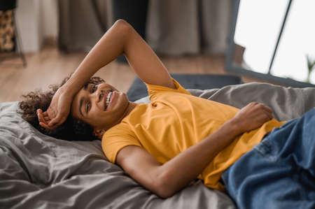 Curly-haired young mulatto resting at homeの写真素材