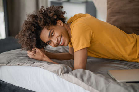 Young curly-haired dark-skinned man resting at homeの写真素材