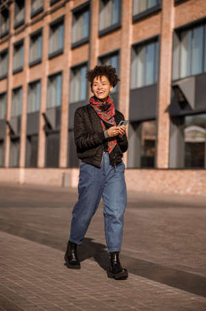Dark-haired young girl in jacket and jeans in the streetの写真素材