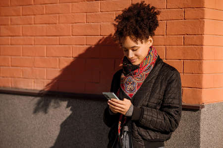 Dark-haired young girl in jacket with a phone in handsの写真素材