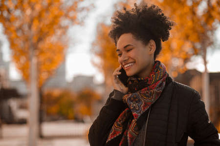Curly-haired smiling girl talking on the phoneの写真素材