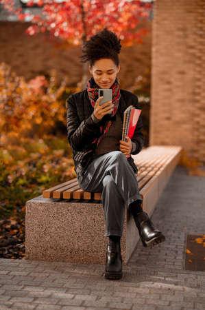 Dark-haired cute young girl sitting with a phone in handsの写真素材