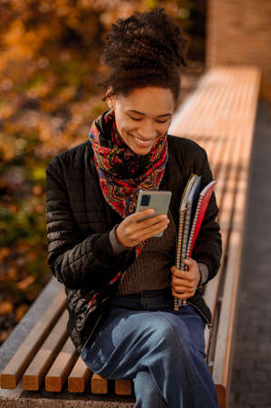 Dark-haired cute young girl sitting with a phone in handsの写真素材