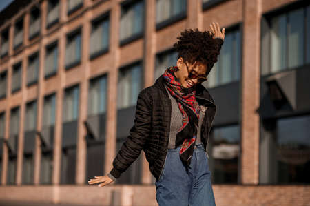 Good mood. A dark-skinned girl in sunglasses walking in the street and feeling joyfulの写真素材