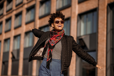 A dark-skinned girl in sunglasses walking in the street and feeling joyfulの写真素材