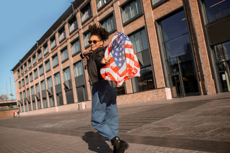A dark-skinned girl with american flag in handsの写真素材