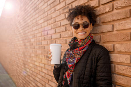 A cute girl in sunglasses having coffee outsideの写真素材