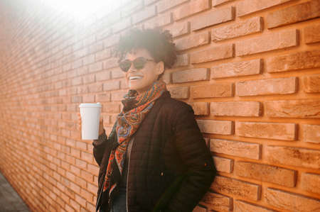 A cute girl in sunglasses having coffee outsideの写真素材