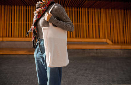 A young woman with a linen bag standing in the streetの写真素材