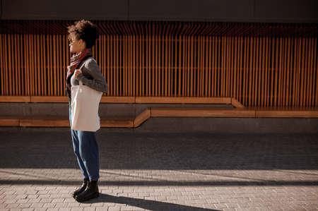 A young woman with a linen bag standing in the streetの写真素材