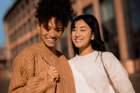 Two pretty girls walking and talking, feeling joyfulの写真素材
