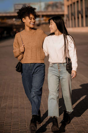 Two pretty girls walking and talking, feeling joyfulの写真素材